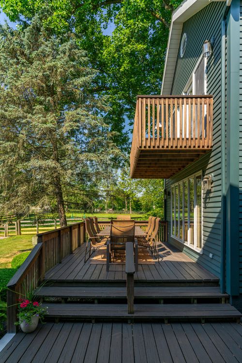 Wood deck with outdoor dining table set beneath a cantilevered second-floor balcony