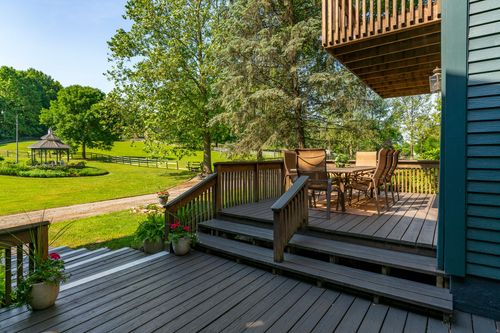 Multi-level wood deck with dining table overlooking a lawn and distant gazebo
