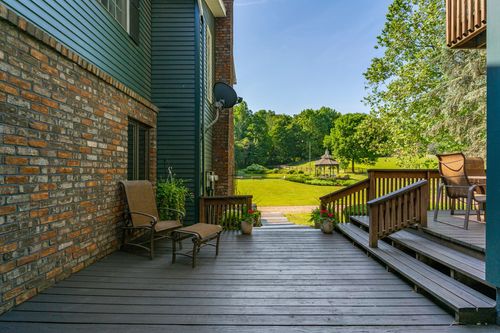 Brick and blue-gray home exterior with a wood deck, patio chairs and garden view