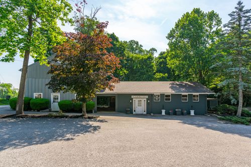 Gray barn-style outbuilding with a covered breezeway and paved parking area
