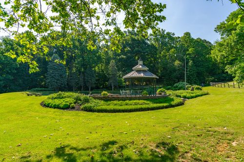 Ornate garden gazebo set on a circular lawn surrounded by manicured flower beds