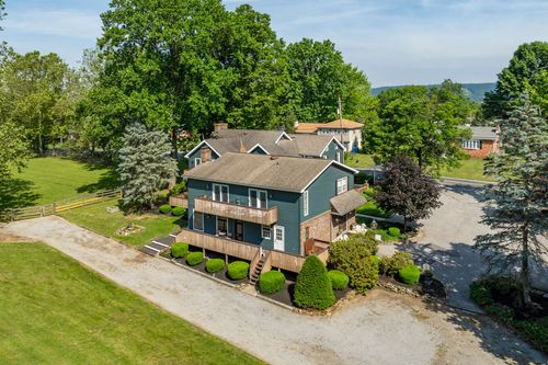 Aerial view of a farmhouse with a second-floor balcony and outdoor staircase to the yard