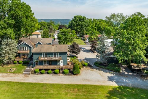 Aerial view of a farmhouse with covered porches and a small garden pond feature