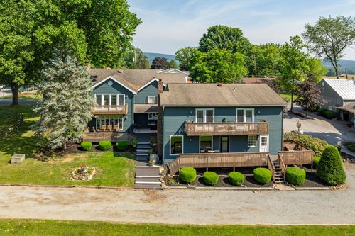 Aerial view of a farmhouse rooftop with dormers surrounded by mature landscaping