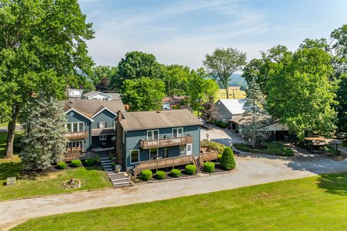 Aerial view of a farmhouse and a white pole building nestled among tall evergreen trees