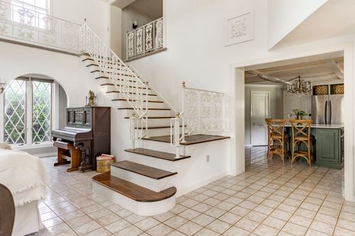 Entry hall with a curved staircase, wrought iron railing and a view into the kitchen