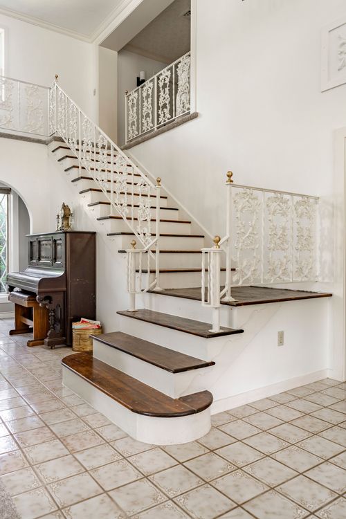 Close view of a curved staircase with white iron balusters and wood treads