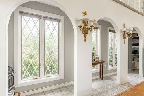 Hallway with diamond leaded-glass windows and ornate brass wall sconces