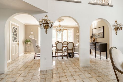 Foyer with a series of arched openings leading to a chandelier-lit dining room