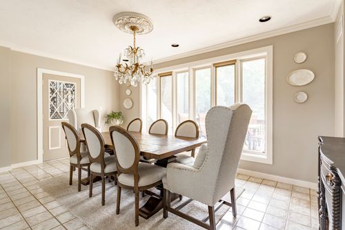 Dining room with a long wood table, crystal chandelier and a wall of windows