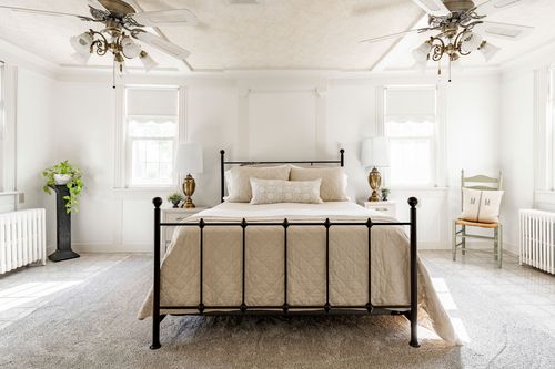 Primary bedroom with a wrought iron bed frame and dual ceiling fans