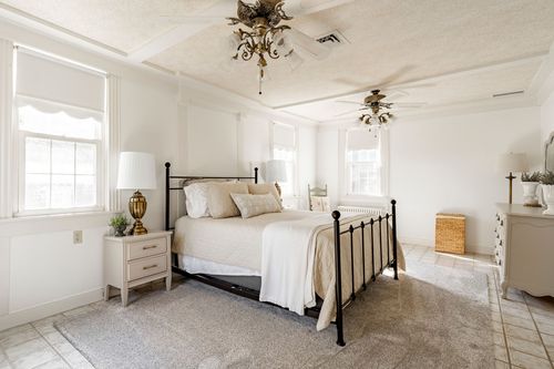 Bedroom with a coffered ceiling, iron bed frame and neutral bedding