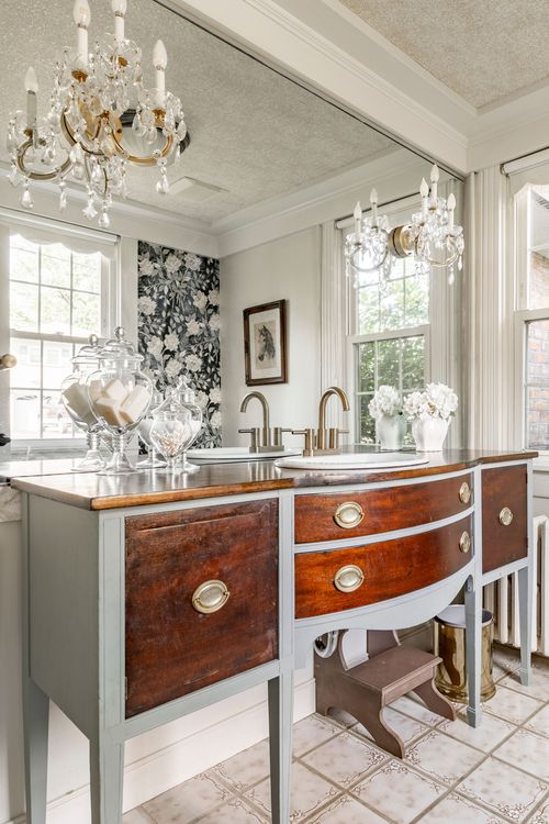 Bathroom vanity made from a repurposed antique dresser, beneath a crystal chandelier