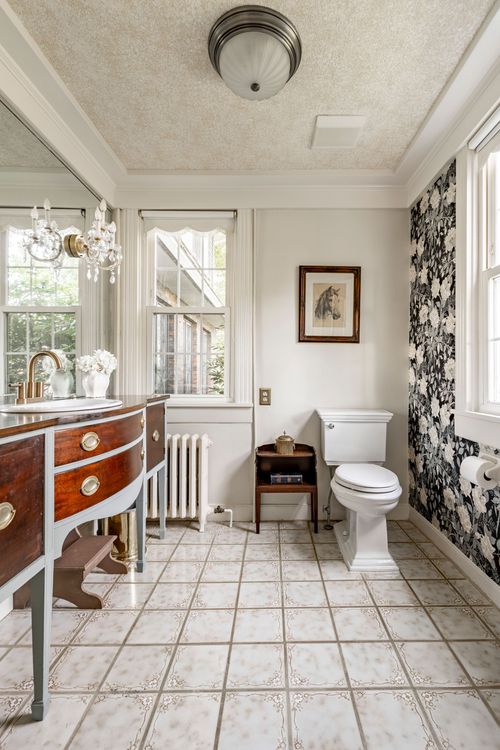 Bathroom with an antique wood vanity, radiator and black floral wallpaper accent