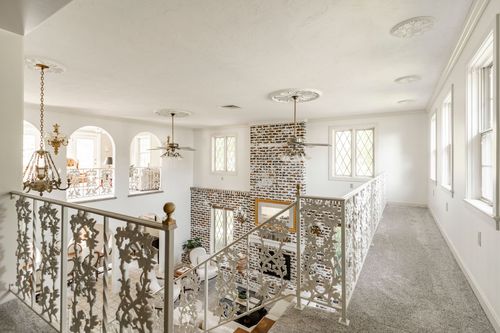 Upstairs landing overlooking an ornate wrought iron staircase railing