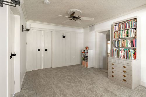 Bonus room with white board-and-batten closet doors and a ceiling fan