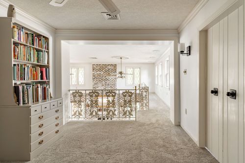 Upper-level reading nook with a built-in bookcase overlooking the stairwell