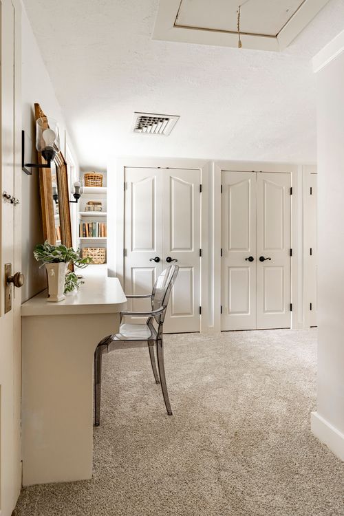 Hallway with a built-in desk nook beneath a closed attic access hatch