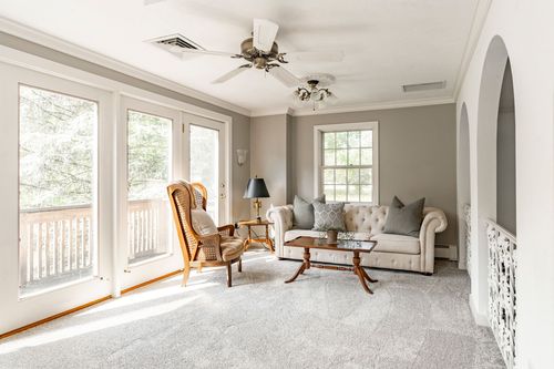 Sunroom sitting area with French doors to a balcony and a tufted loveseat