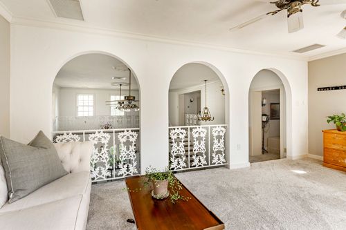 Loft sitting area with three arched openings over a wrought iron stair rail