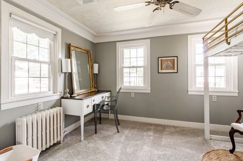 Bedroom with a gilt mirror over a white vanity desk and a radiator