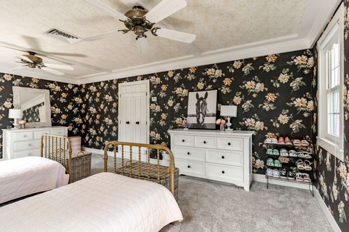 Bedroom with floral wallpaper, a white dresser and a horse print above a shoe rack