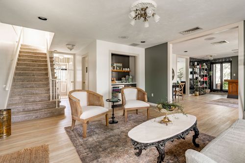 Living room with a staircase, built-in bookshelf nook and cane barrel chairs