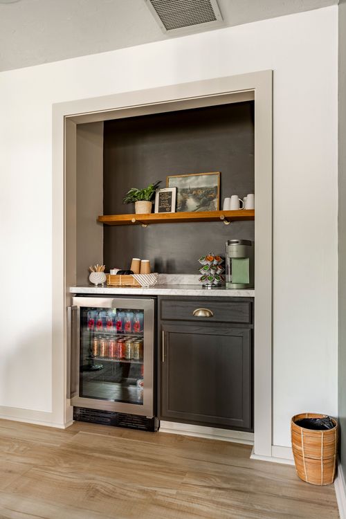 Built-in beverage bar with a wine fridge, marble counter and dark accent wall