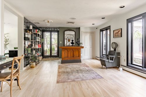 Salon reception hallway with a dark bookshelf, wood desk and accent wall