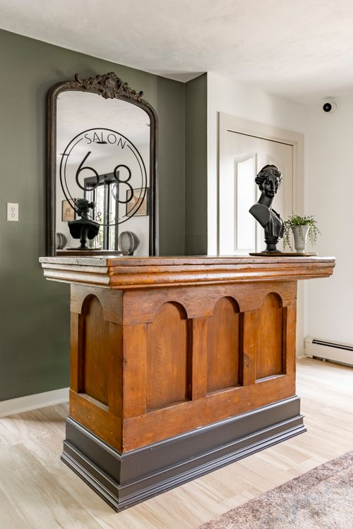 Antique wood reception desk beneath an ornate mirror reading Salon 68