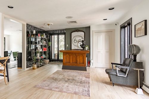 Salon waiting area with a wood reception desk, dark bookshelf and hooded dryer chair
