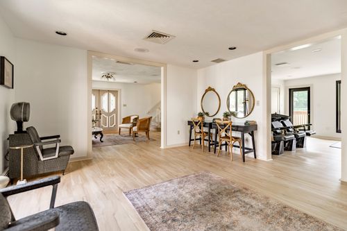 Hallway with round gilt mirrors over a black console desk and cross-back chairs