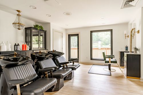 Salon shampoo station with black reclining chairs and a gold pendant chandelier