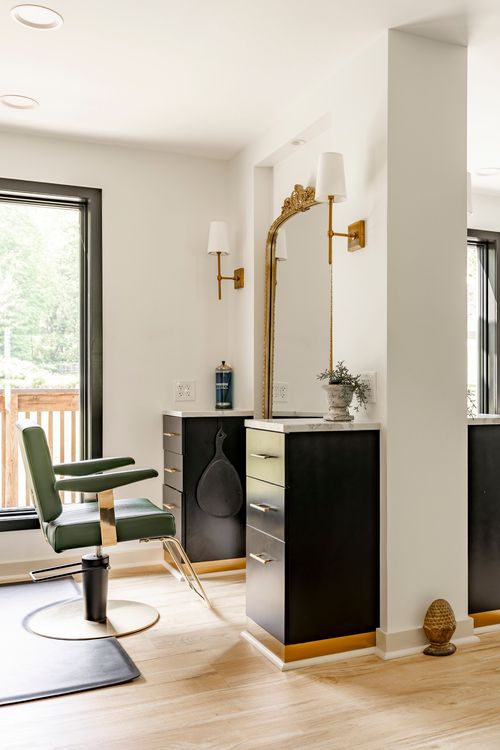 Single salon station with a green leather chair, black cabinet and arched gilt mirror