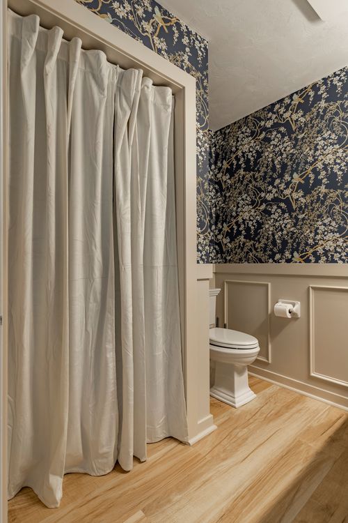 Bathroom with navy floral wallpaper and a curtained nook beside the toilet