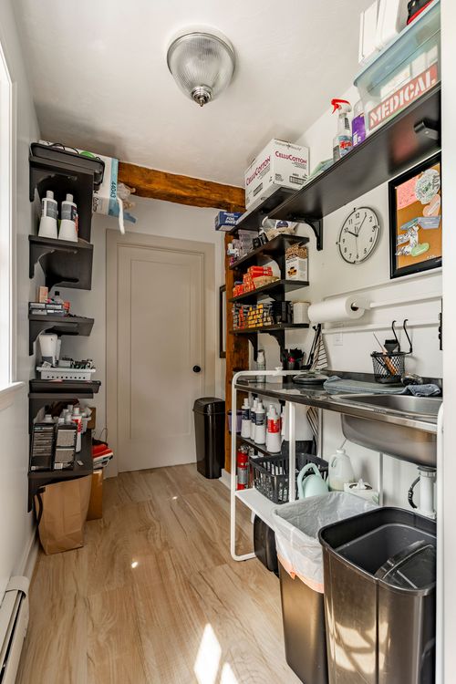 Utility pantry room with stocked open shelving, exposed beam and a stainless sink