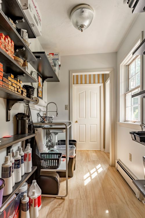 Laundry and utility room with open shelving, a farmhouse sink and wood flooring