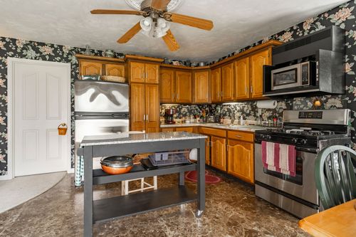 Kitchen with oak cabinets, floral wallpaper backsplash and a stainless refrigerator