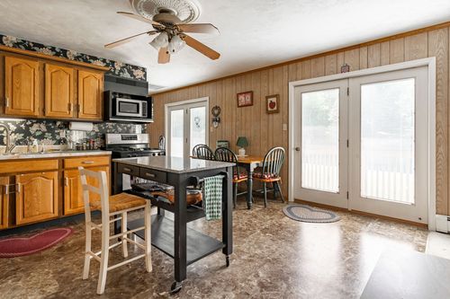 Kitchen with oak cabinetry and floral wallpaper opening to a dining nook with French doors