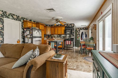 Open living and kitchen area with floral wallpaper, oak cabinets and a dining table