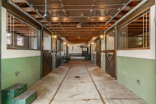 Horse barn aisle with wood plank stalls and green cinder block wainscoting
