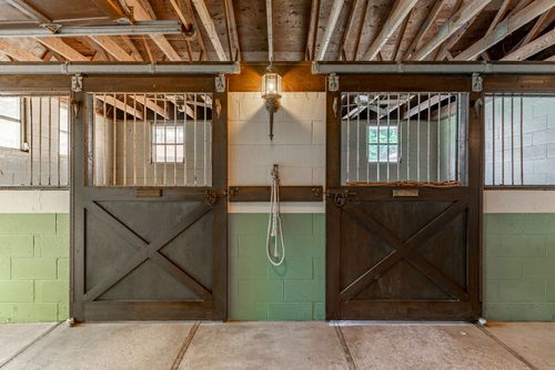 Two barn stall dutch doors with wire grilles and a hanging lead rope between them