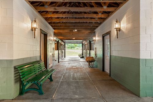 Barn breezeway with exposed wood trusses, lantern sconces and a green bench