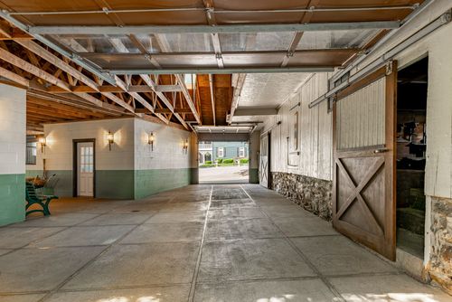 Barn corridor with cinder block walls, exposed roof trusses and a sliding wood door