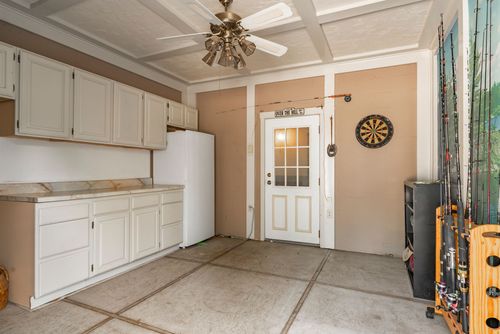 Garage nook with white cabinetry, a coffered ceiling, dartboard and paneled entry door