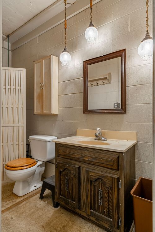 Barn bathroom with a wood vanity, globe pendant lights and cinder block walls