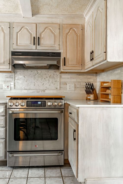 Stainless range beneath exposed beams, with a knife block and built-in spice rack