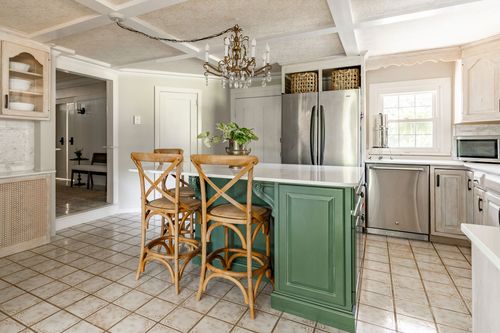 Kitchen island with green cabinetry, stainless appliances and a wood beam ceiling