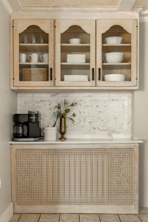 Built-in coffee nook with glass-front cabinets, marble herringbone backsplash and a Keurig
