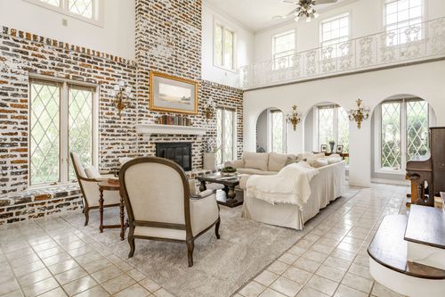 Great room with a brick fireplace wall, cream sofa and tall arched leaded-glass windows